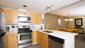 a kitchen with a stove and a sink and a table at Woodrun Lodge 211 | Ski-In Ski-Out Condo w/ Heated Pool, Hot Tub, Parking, & Gym in Whistler