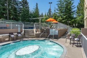 a swimming pool with chairs and an umbrella at Woodrun Lodge 211 | Ski-In Ski-Out Condo w/ Heated Pool, Hot Tub, Parking, & Gym in Whistler