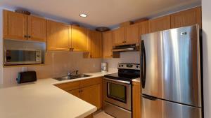 a kitchen with wooden cabinets and a stainless steel refrigerator at Woodrun Lodge 416 | Family Ski-In Ski-Out Condo, Hot Tub, Heated Pool, Parking & Laundry in Whistler