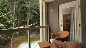 a balcony with two chairs and a large window at Woodrun Lodge 416 | Family Ski-In Ski-Out Condo, Hot Tub, Heated Pool, Parking & Laundry in Whistler