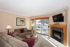 a living room with a couch and a fireplace at Woodrun Lodge 302 | Large Condo w/ Shared Heated Pool & Large Hot Tub in Whistler