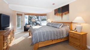 a bedroom with a bed and a flat screen tv at Woodrun Lodge 302 | Large Condo w/ Shared Heated Pool & Large Hot Tub in Whistler