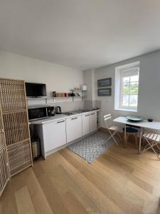 cocina con armarios blancos, mesa y ventana en Appartement 2 pièces quartier des Mielles, en LʼIsle-Saint-Cast