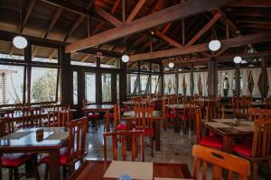 a restaurant with wooden tables and chairs and windows at Hotel Raul's in Gaspar