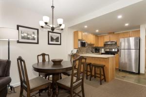 a kitchen with a table and a stainless steel refrigerator at Woodrun Lodge 414 | Cozy Ski-In Ski-Out Condo w/ Shared Hot Tub, Pool, Fireplace, & Parking in Whistler
