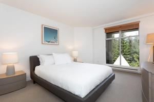 a white bedroom with a bed and a window at Woodrun Lodge 417 | Ski-In Ski-Out, Pool, Hot Tub, Free Parking in Whistler