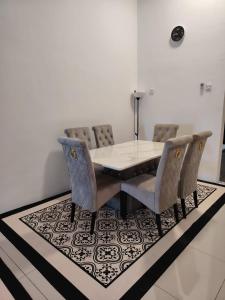 a dining room with a table and chairs on a rug at FH Homestay Kuala Lipis 3R2B in Kuala Lipis