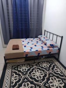 a bed in a room with blue curtains and a rug at FH Homestay Kuala Lipis 3R2B in Kuala Lipis +1 photo