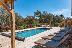 una piscina con tumbonas en una terraza de madera en Villa Campemu Di Lecci, en Lecci