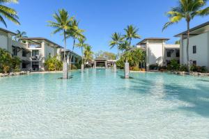 a swimming pool at a resort with palm trees at Lagoon Sanctuary - Resort Living by Four Mile Beach in Craiglie