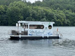 a white boat is floating on a lake at Hausboot Rollyboot Evolution- feste Unterkunft am Steg in Joachimsthal +16 photos