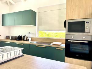 a kitchen with green cabinets and a microwave oven at Villa TULIA in Sainte-Luce +7 photos