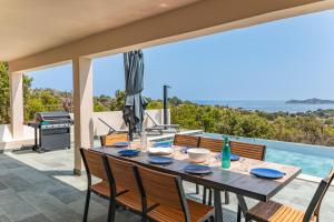una mesa de comedor con sillas y una parrilla en el patio en Villa Vista Di Pinarello, en Pinarellu
