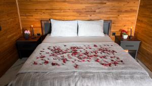 Una cama con rosas rojas en ella con dos mesitas de noche en Trabzon Bungalov, en Akcaabat