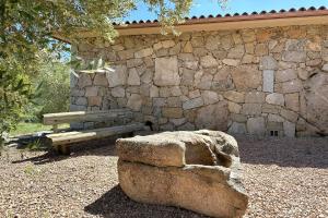 un mur de pierre avec un banc à côté d'un rocher dans l'établissement Villa Taglio Rosso Di Santa Lucia, à Sainte-Lucie de Porto-Vecchio