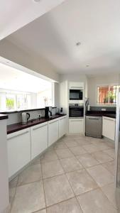 une grande cuisine avec des armoires et des appareils blancs dans l'établissement Villa Taglio Rosso Di Santa Lucia, à Sainte-Lucie de Porto-Vecchio 25 autres photos