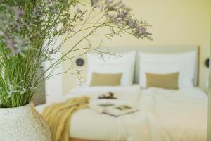 a white vase filled with flowers next to a bed at oceanHUTS Coxos Adults Only from age 14 in Ericeira