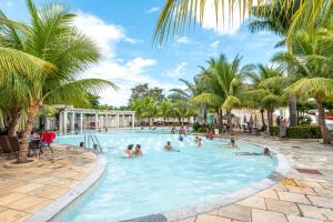 a group of people in a swimming pool with palm trees at diRoma Lacqua V direto com o Grupo diRoma com acesso ao Acqua Park e Café da manhã in Caldas Novas
