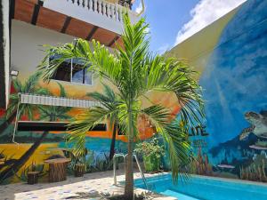 Una palmera frente a una pared con un mural. en Casa Coralite, en Santa Marta