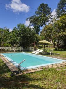 a blue swimming pool with a table and an umbrella at Sítio Nosso Cantinho in Mogi das Cruzes