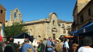 un grupo de personas parados en un mercado frente a una iglesia en Cal Jordi, Fulleda, en Fulleda