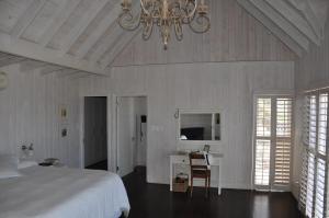 布菲尔斯巴埃Main beachfront house Halleluja II, Buffalo Bay的一间卧室配有一张床、一张书桌和一个吊灯。