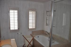 布菲尔斯巴埃Main beachfront house Halleluja II, Buffalo Bay的一间带浴缸和淋浴的浴室以及两个窗户。