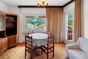 una sala da pranzo con tavolo, sedie e una finestra di Casa Al Sole Moena a Moena