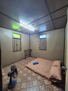 a room with a bed and a fan in it at Homestay Sayang Salmah in Balik Pulau +5 photos
