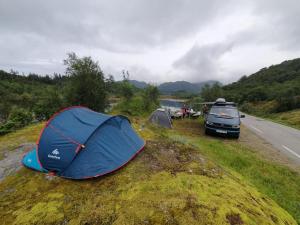 una tenda blu e un'auto parcheggiate sul ciglio di una strada di Mitsubishi med telt og camping utstyr a Sandnes