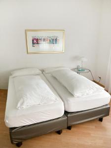 twee witte bedden in een kamer met een foto aan de muur bij MAVO Hospitality Stuttgart Marienplatz in Stuttgart