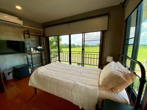 a bedroom with a bed and a large window at Nature Peace Home in U Thong
