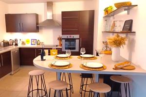 une cuisine avec une table et des tabourets dans l'établissement Appartement Les Hameaux de Pinarello, à Sainte-Lucie de Porto-Vecchio