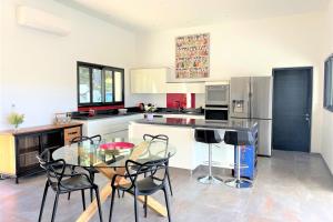 cocina con mesa de cristal y sillas negras en Villa Montinu Di Caramontinu, en Sainte-Lucie de Porto-Vecchio