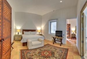 a bedroom with a bed and a chair and a television at Hotel Boutique Casareyna in Puebla +19 photos
