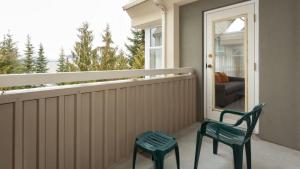 two green chairs sitting on a porch with a window at Woodrun Lodge 517 | Large Ski-In Ski-Out Condo by Upper Village w/ Mountain Views & Shared Hot Tub in Whistler +19 photos