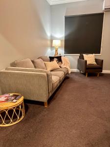 un soggiorno con divano e grande schermo di Wattle Cottage a Cootamundra