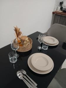 a black table with plates and glasses and a basket at CAYENNE Centre Studio D'ESTREE ECO LUXE in Cayenne +7 photos