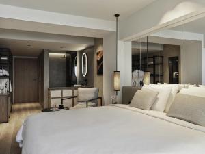 a bedroom with a large white bed and a kitchen at NIKO Seaside Resort MGallery in Agios Nikolaos +133 photos