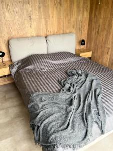 a bed with a gray blanket on top of it at Laimeskalni in Koknese