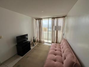 a living room with a large pink couch in front of a window at La Serena, Vista al mar y piscina in Coquimbo