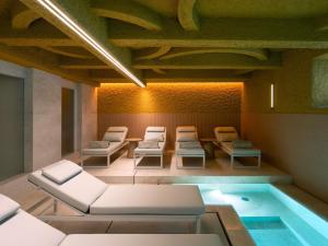 Cette chambre dispose d'une piscine, de chaises et d'une table. dans l'établissement Palazzo Tirso MGallery Cagliari, à Cagliari