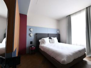 a bedroom with a bed with white sheets and pillows at Palazzo Tirso MGallery Cagliari in Cagliari