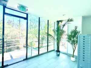 a room with large glass windows and plants in it at Modern New Studio Cozy&Prime Location in North Sherman Way
