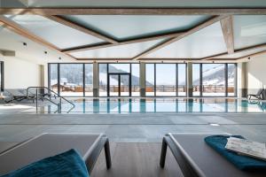 a swimming pool with a view of the mountains at MGM Hôtels & Résidences - Résidence Chalets de Joy in Le Grand-Bornand