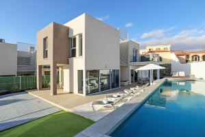 a villa with a swimming pool in front of a house at Nirvana - Luxury Villa with heated pool in Playa Paraiso