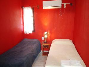 a red room with two beds and a window at Casa de Foxie in San Agustín de Valle Fértil