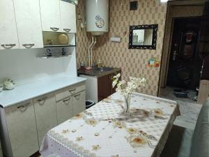 サマルカンドにあるYasmin Apartmentの花瓶に花が飾られたテーブルのあるキッチン