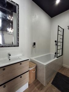 un bagno con vasca, lavandino e specchio di La discrète romantique, appartement avec jacuzzi a Charavines