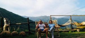 two people sitting in chairs on a hammock in the mountains at Qaldea Resort in Ushguli